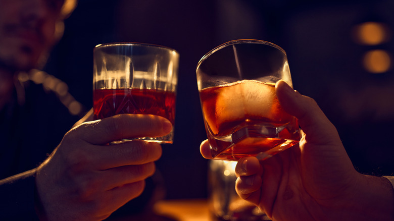 Hands holding glasses of bourbon