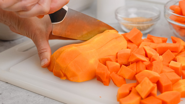 person cutting butternut squash on cutting board