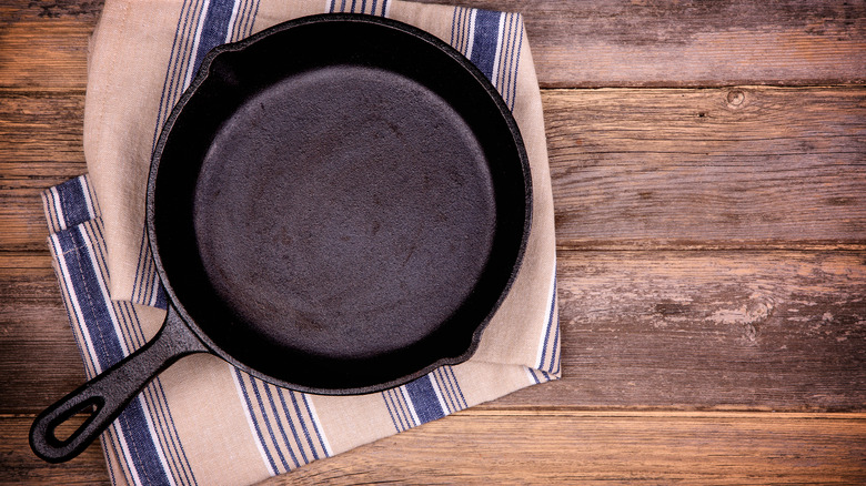 An empty cast-iron skillet sitting on a tea towel.