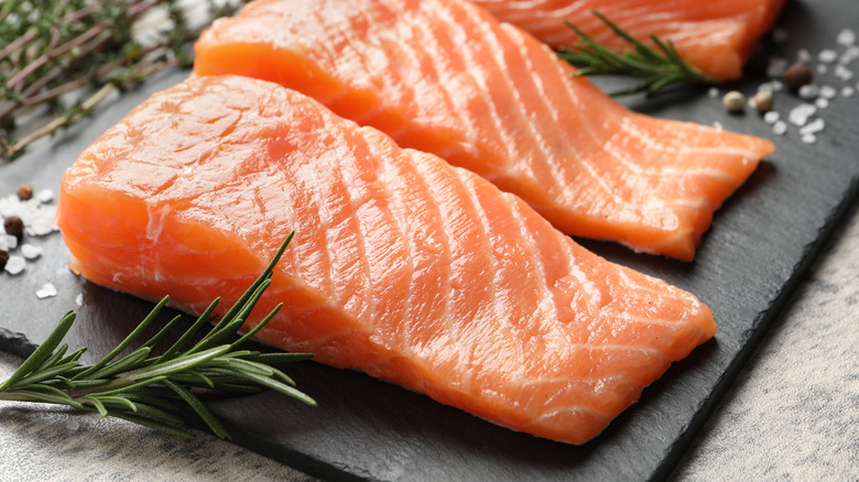 Fresh salmon slices with sprigs of herbs around it