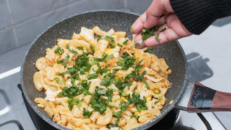 Cooking pasta in a pan with herbs