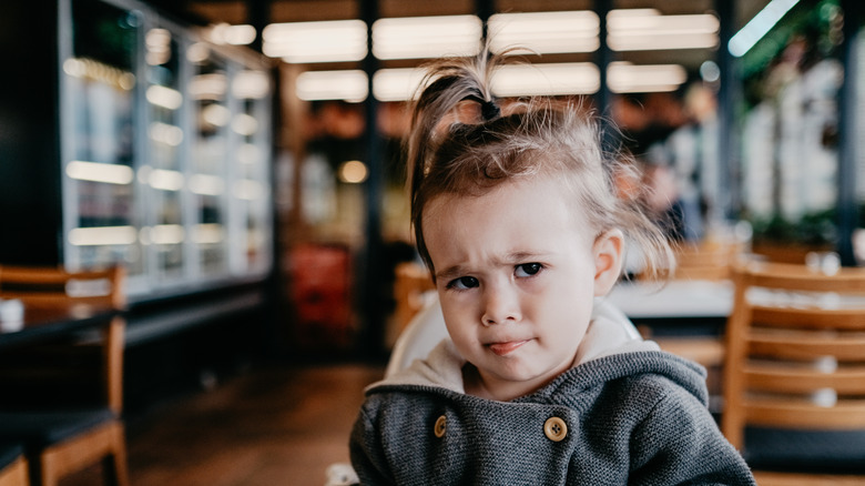 A small child in a highchair at a restaurant