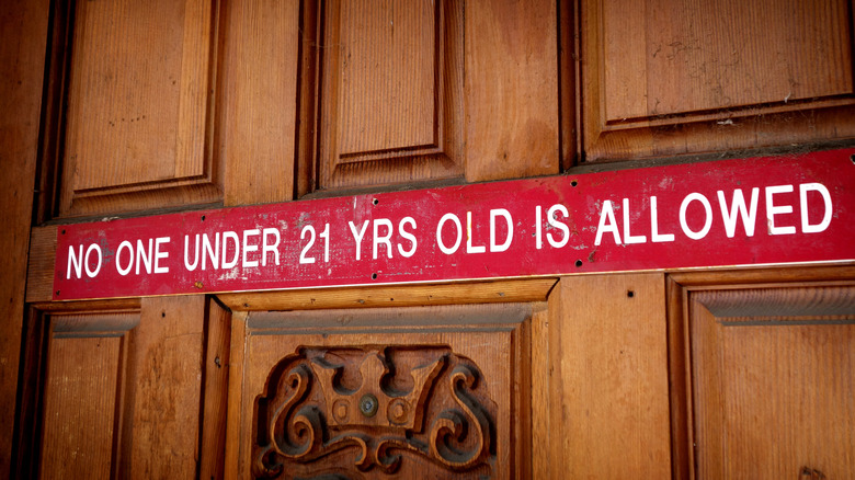 A sign on a wooden door reading: No one under 21 years old is allowed