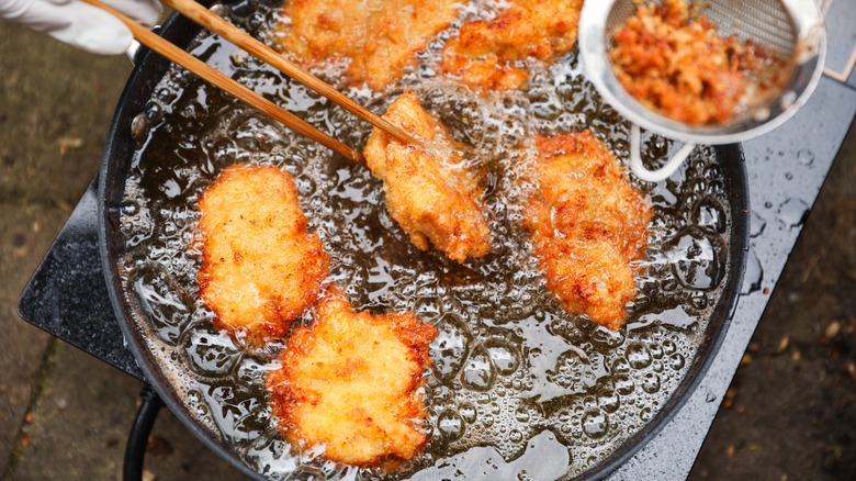 golden, crispy fried chicken pieces in bubbling oil, symbolizing indulgence and temptation