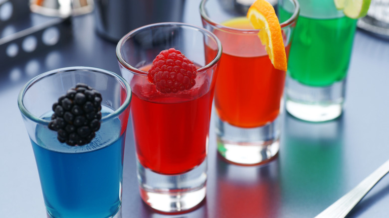 Colorful Jell-O shots in glasses with fruit garnishes