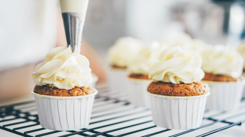 Frosting being piped onto cupcakes.