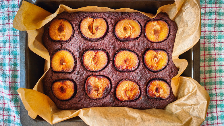 Plum cake in a metal pan with parchment paper