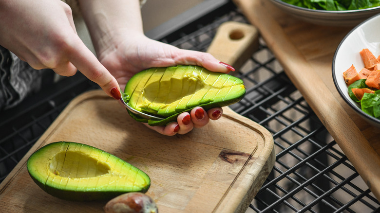 Person removing avocado slices from peel