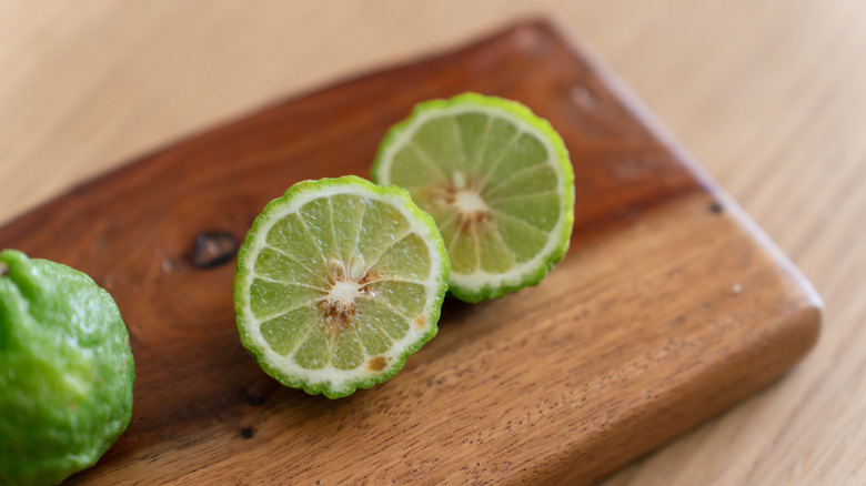 Limes cut in half and placed on a wooden board.
