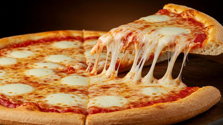 Slice of cheese pizza being pulled away from full pie