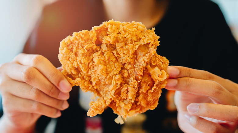 Hands holding fried chicken