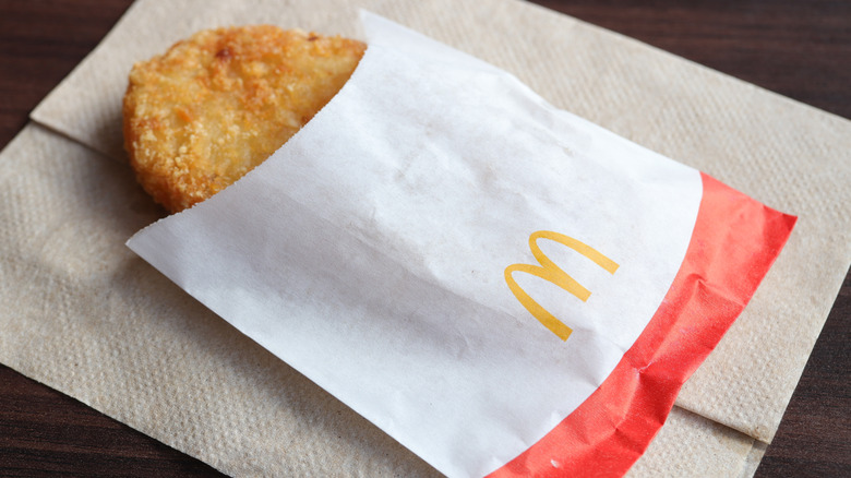 A McDonald's hash brown in its sleeve on a paper napkin