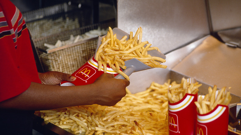 McDonald's employee scooping fries into a fry carton