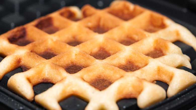 Close up of a waffle in a waffle iron.