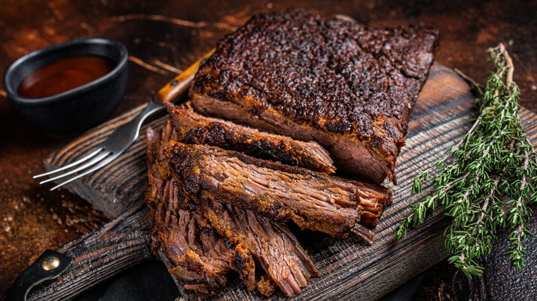 Charred brisket sliced on a wooden cutting board.