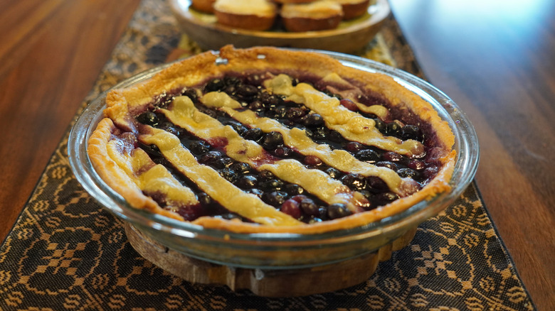 Blueberry pie in a glass baking dish on a table runner on a wooden table