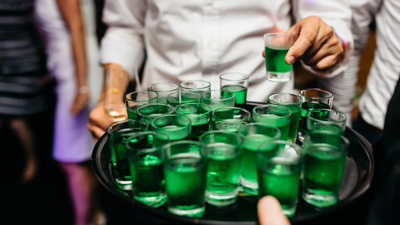 Someone taking a green jello shot from a server.