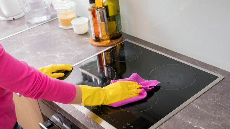 Person cleaning glass cooktop with a microfiber cloth