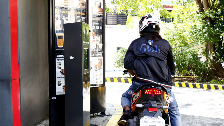 A motorcyclist ordering at a drive-thru speaker
