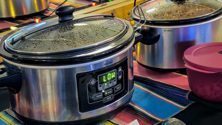 Two Crock-Pots full of food on colorful cloth on a countertop