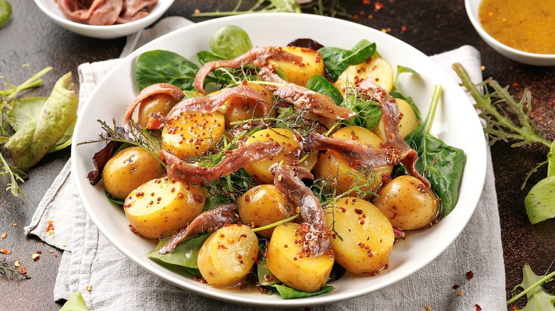 Bed of fresh spinach with small cooked gold potatoes and sardines in a grainy mustard sauce.