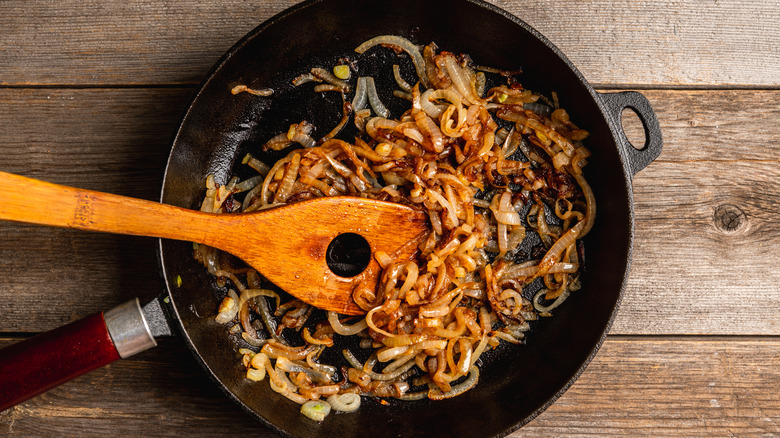 Caramelized onions cook in a cast iron pan