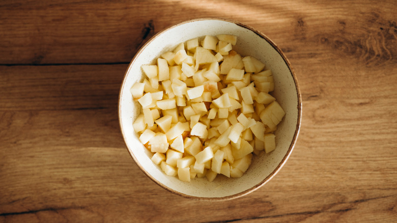 cup of freshly diced apples on a wooden board