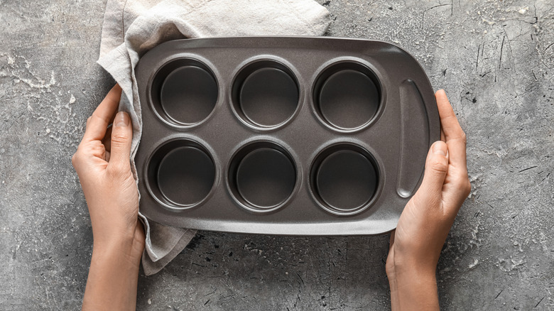 hands holding muffin tin