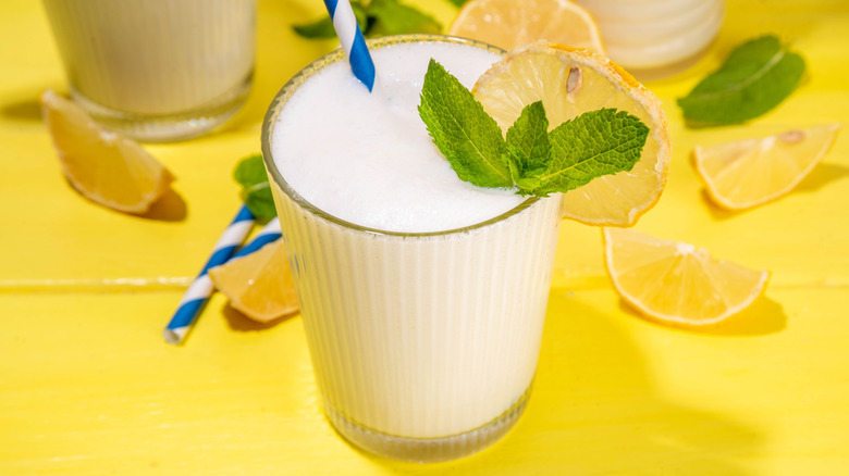 A glass of creamy coconut lemonade with mint and lemon garnish