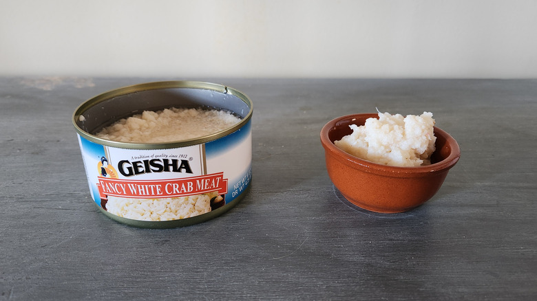 Geisha crabmeat in a can and a small bowl sit on a table.