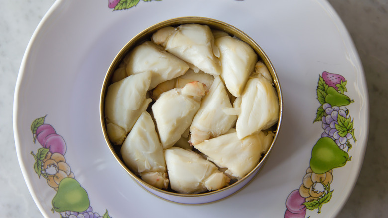Overhead angle of a can filled with lump crab meat on a white plate depicting various fruits