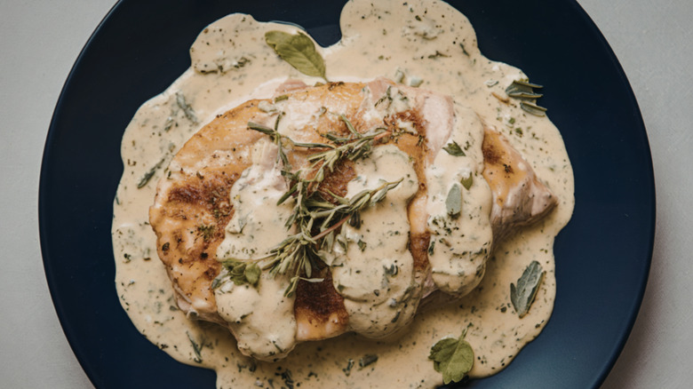 baked chicken breast with a creamy sauce and rosemary sprigs