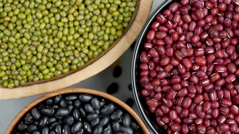 Overhead of red, green, and black dry beans in bowls