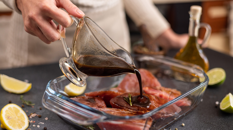 Person pouring marinade over meat