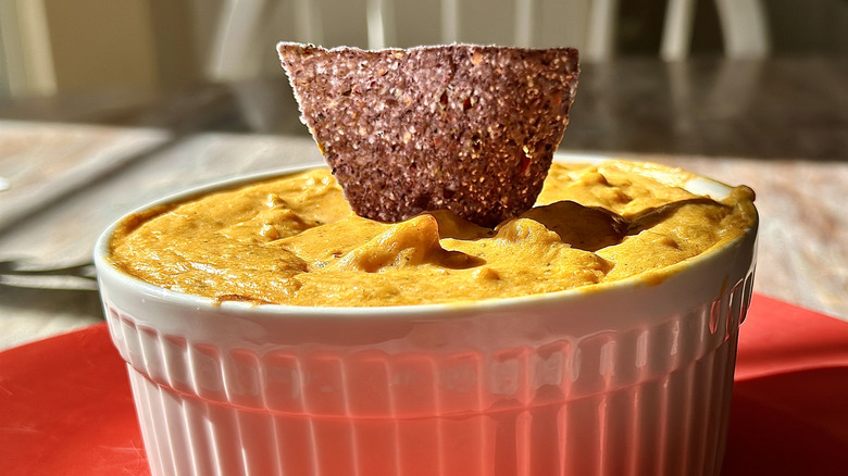 Bowl of Buffalo Chicken dip appetizer with blue corn tortilla chip.