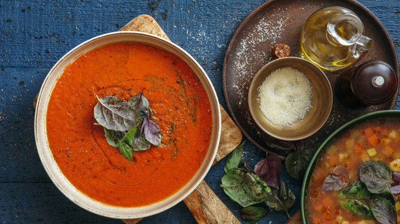 Bowl of soup with cheese and oil on the side.