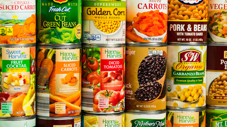 Canned vegetables are stacked on a grocery store shelf.
