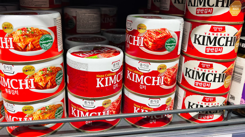 Variety of canned kimchi brands stacked on shelves