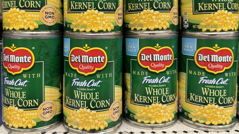 Cans of Del Monte corn are displayed on a store shelf
