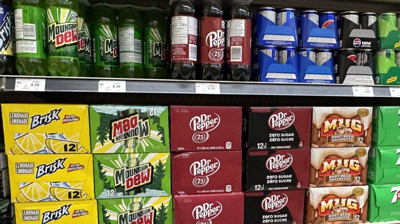 Canned and bottled sodas sit for sale on grocery store shelves.