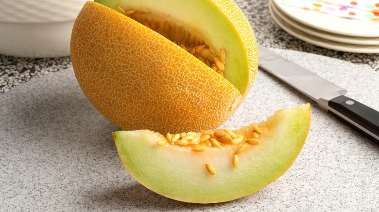 Galia melon with a slice cut out, seeds exposed and overflowing
