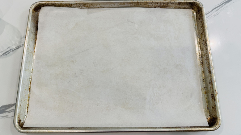 baking sheet lined with parchment paper on marble surface
