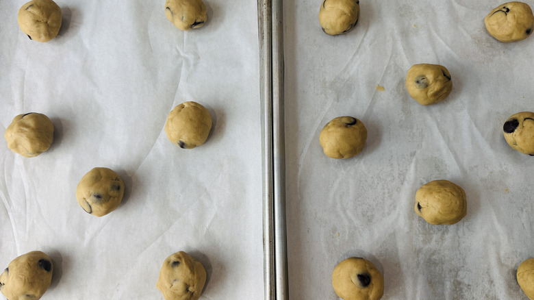 stuffed cookie dough balls arranged on two baking sheets