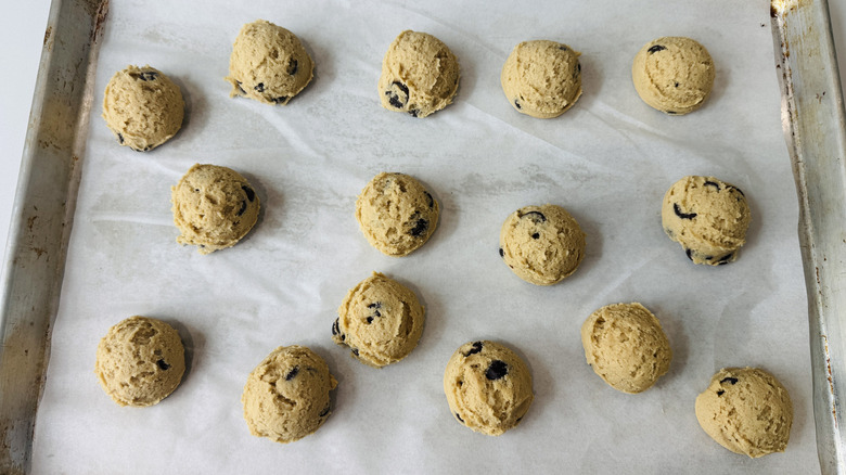 scooped cookie dough arranged on parchment lined baking sheet