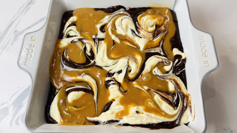 Brownie batter topped with cream cheese and caramel swirls