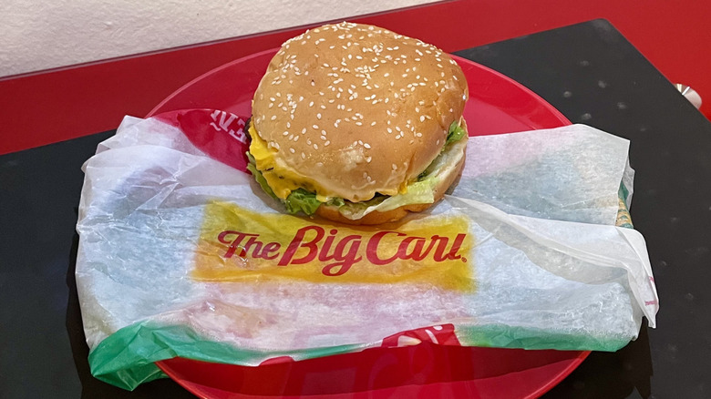 A Big Carl Burger sitting on its wrapper on a plate