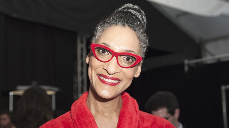 Close-up of Carla Hall smiling in red-framed glasses and red lipstick