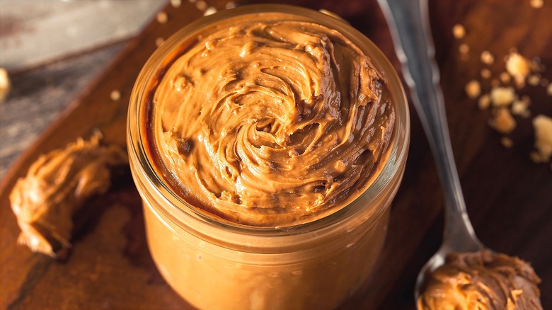 Glass jar filled with cookie butter next to metal spoon