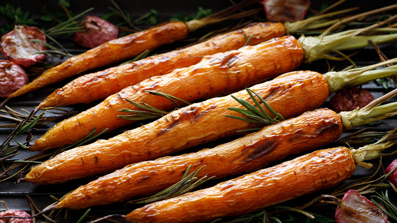 An illustrative image showing several grilled carrots with herbs.