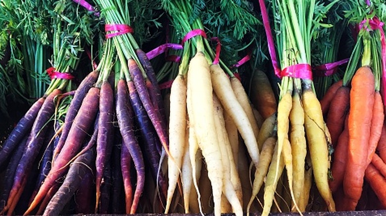 A variety of colourful heritage carrots on an outdoor market stall